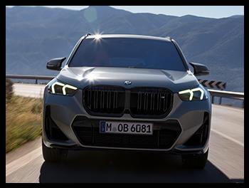 Direkte Frontansicht eines grauen BMW X1 M35i mit der großen, schwarzen Doppelniere, dem M-Logo und den markanten Tagfahrlicht-Elementen.