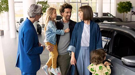 Familie im Gespräch mit einer BMW Mitarbeiterin neben einem Fahrzeug im Autohaus.